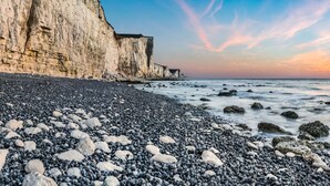 Una playa rocosa con grandes rocas y acantilados al fondo.