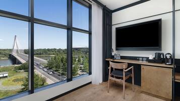 Una habitación moderna con ventanas amplias, un televisor, un escritorio y una silla.