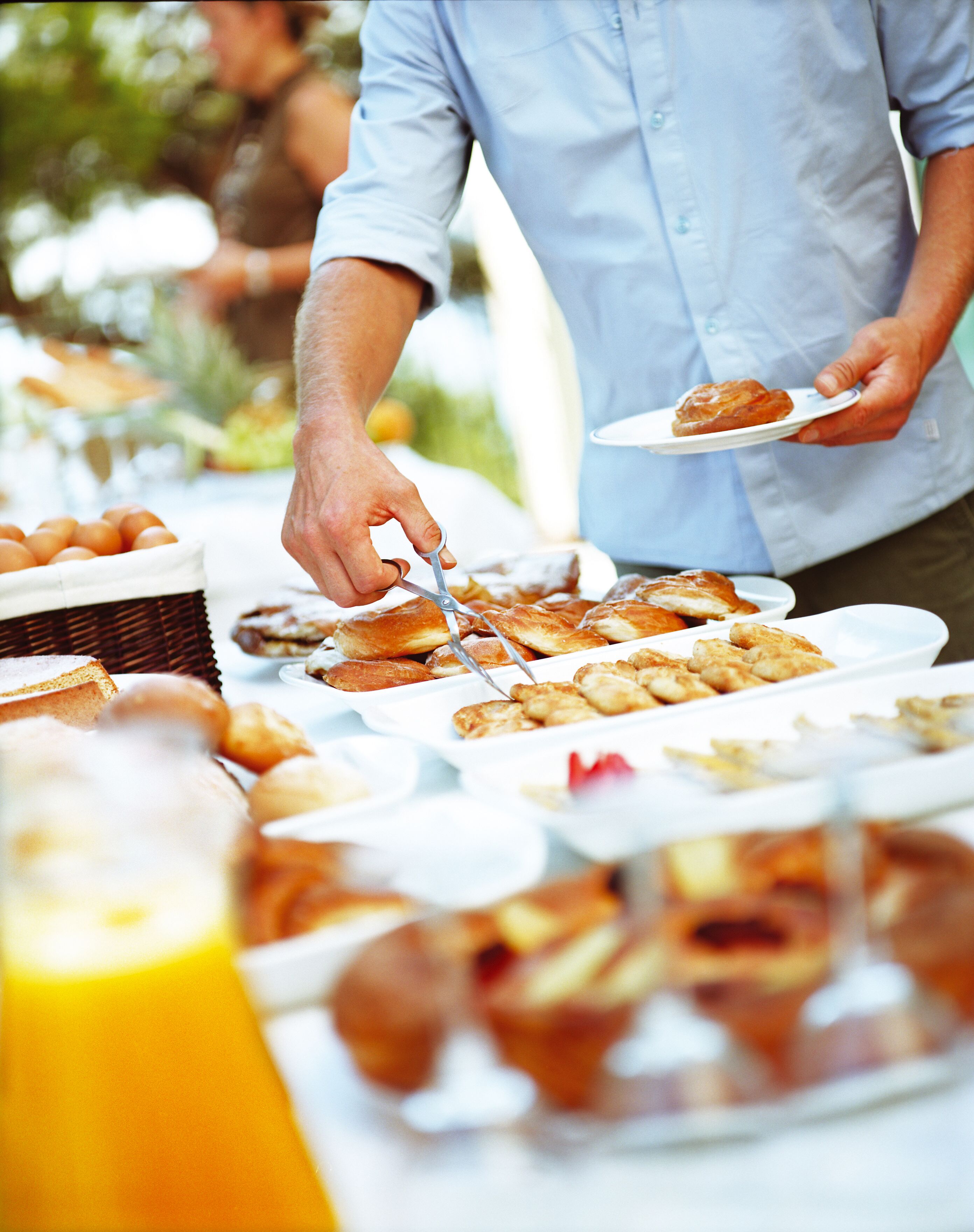 A buffet table with various food items and a person serving themselves.
