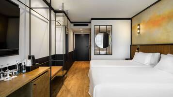 Une chambre d’hôtel moderne avec un grand lit, un bureau doté d’une machine à café, un miroir et un tableau au mur.