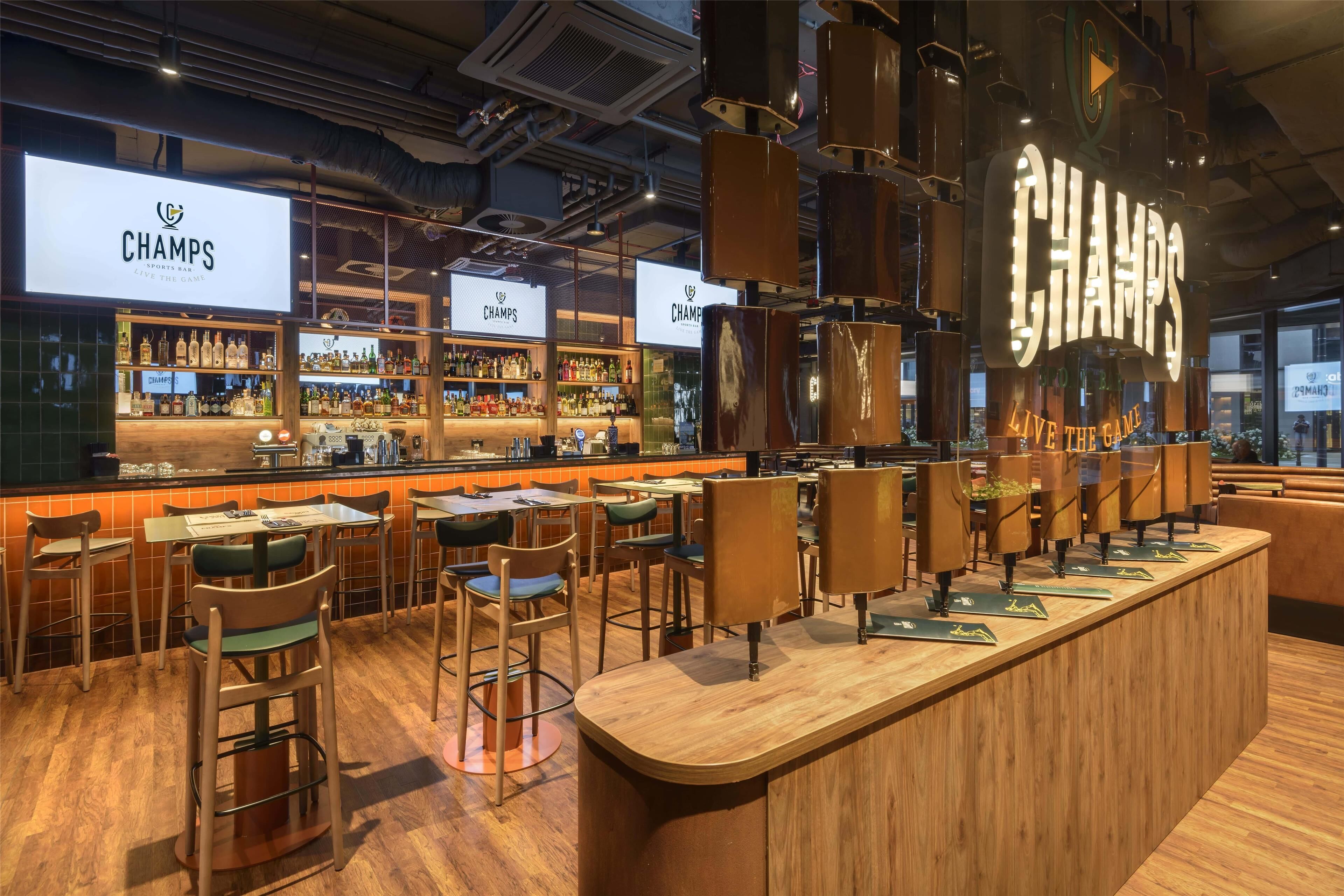 A bar area with multiple seating options, a bar counter, and a large illuminated sign.