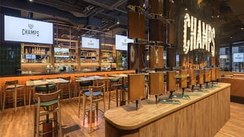 A bar area with multiple seating options, a bar counter, and a large illuminated sign.