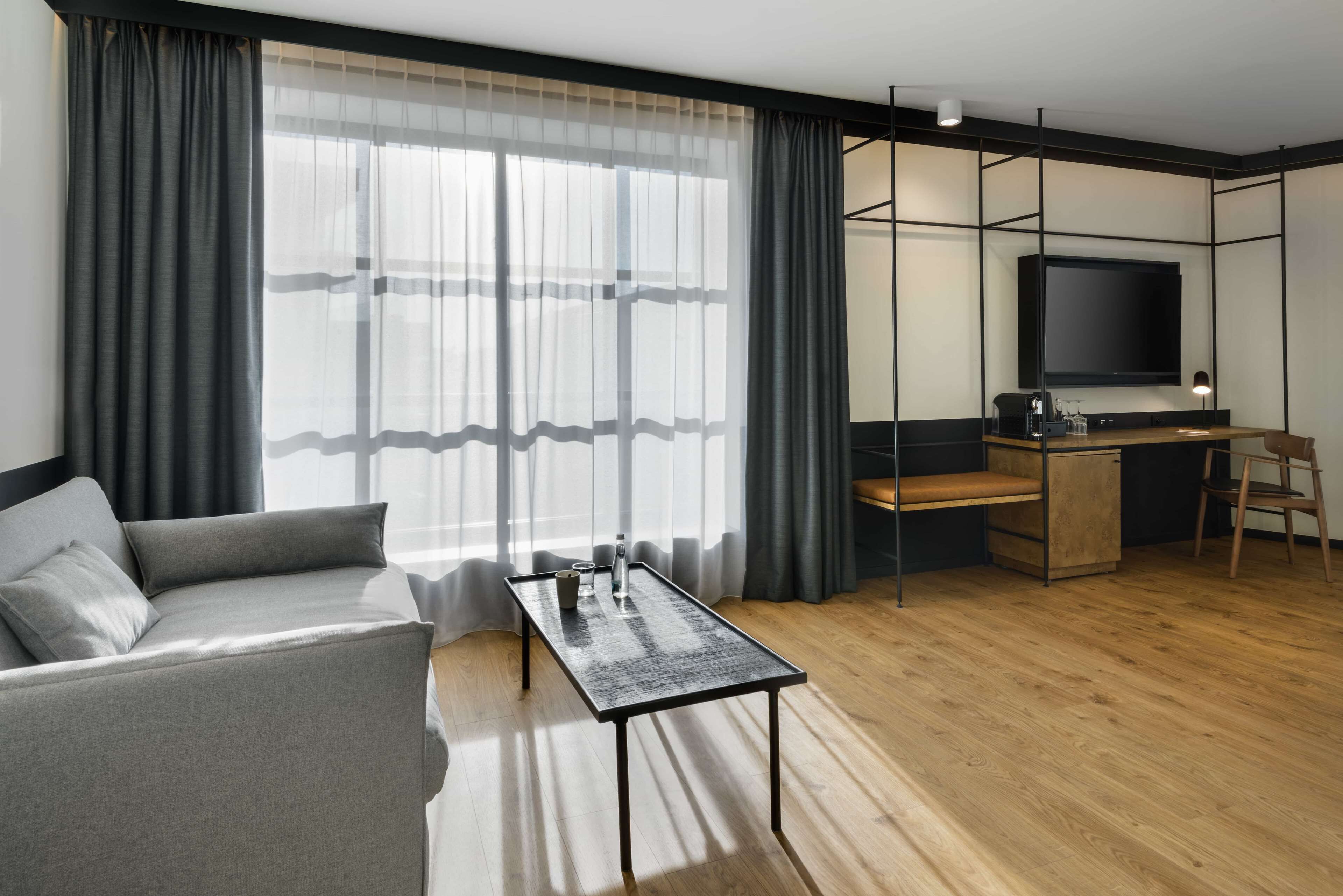 A modern living room with a sofa, a coffee table, a TV, and a desk with a chair.