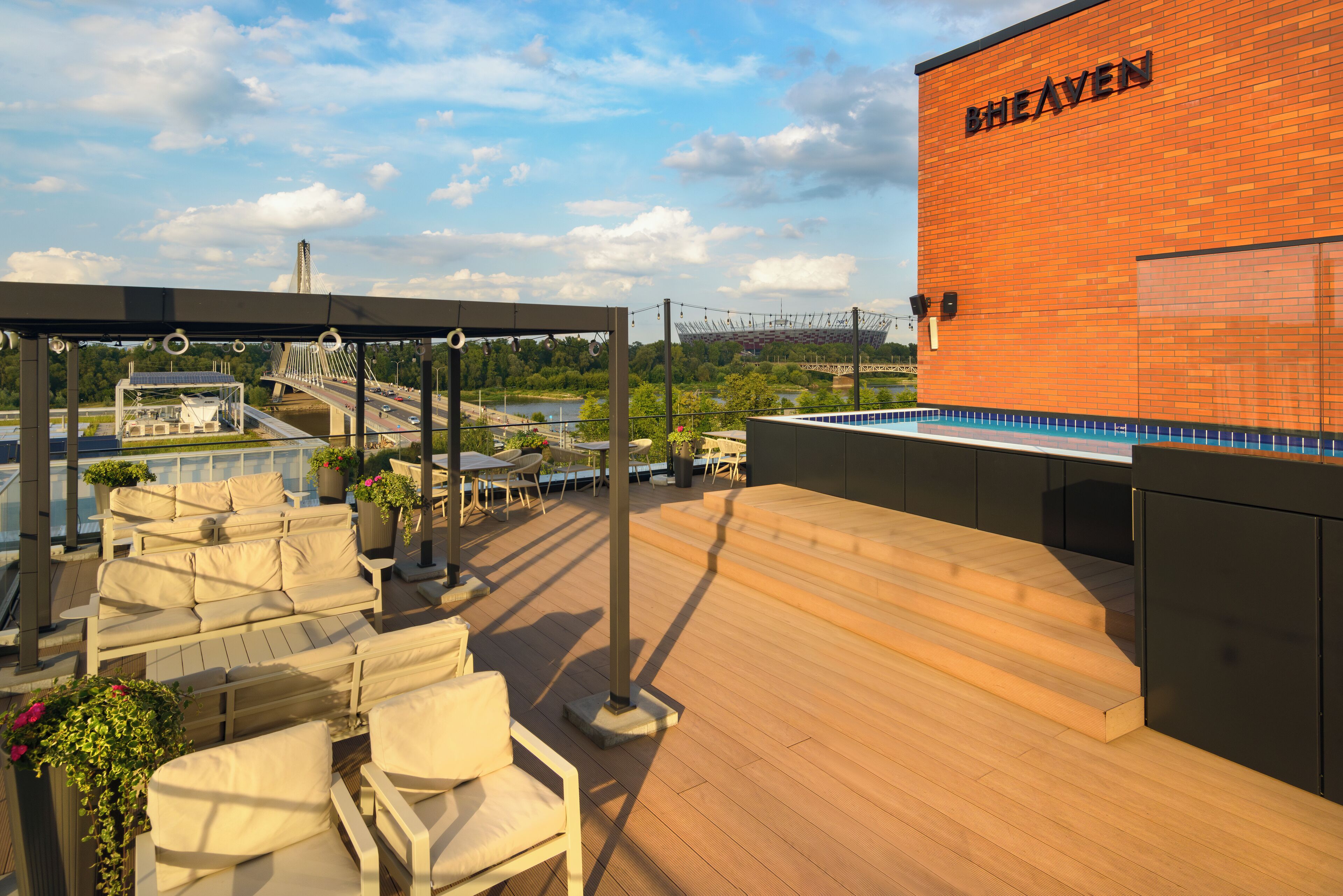 A rooftop terrace with outdoor seating, a view of a bridge, and a building labeled "HEAVEN".