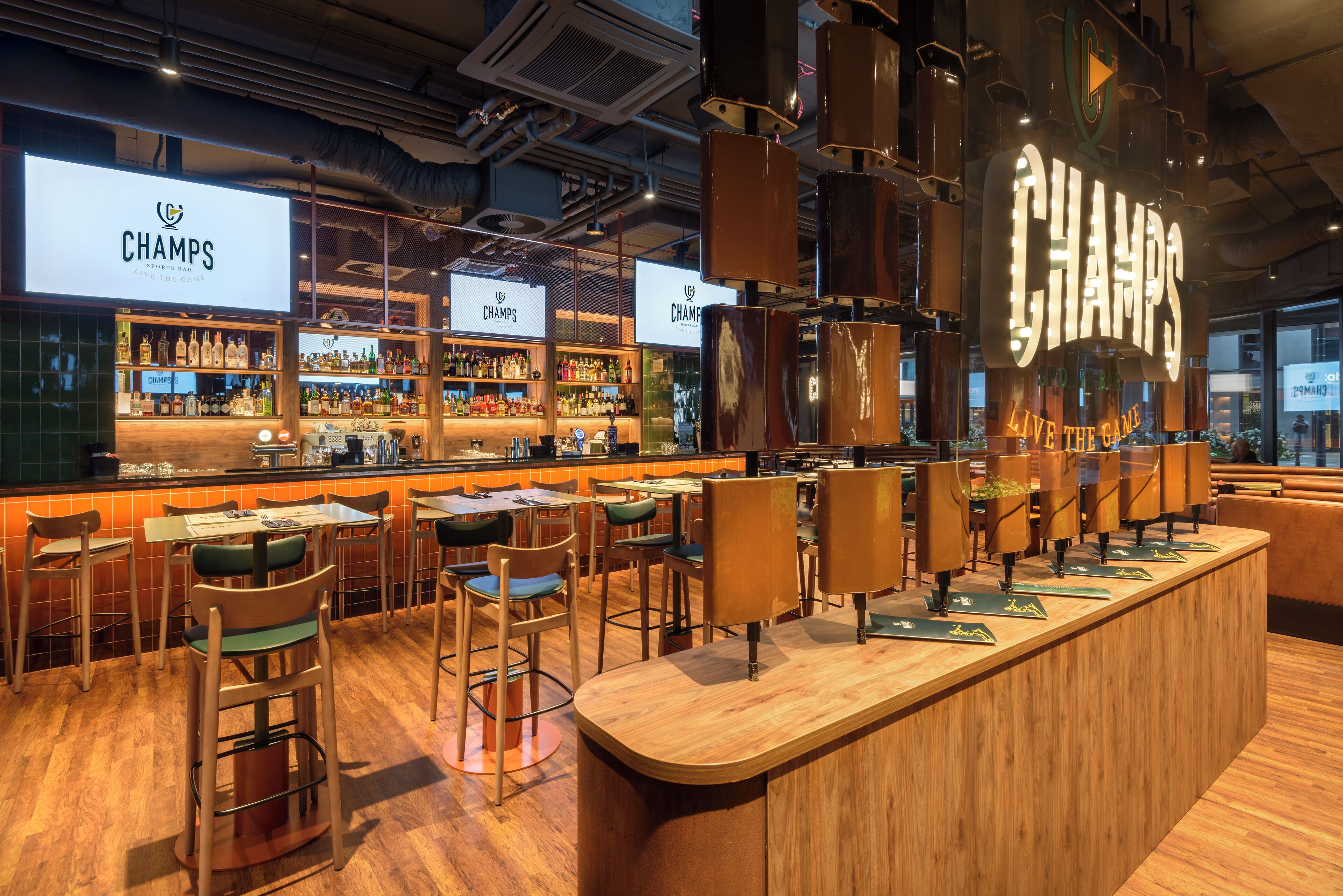 A bar area with multiple seating options, a bar counter, and shelves stocked with bottles.