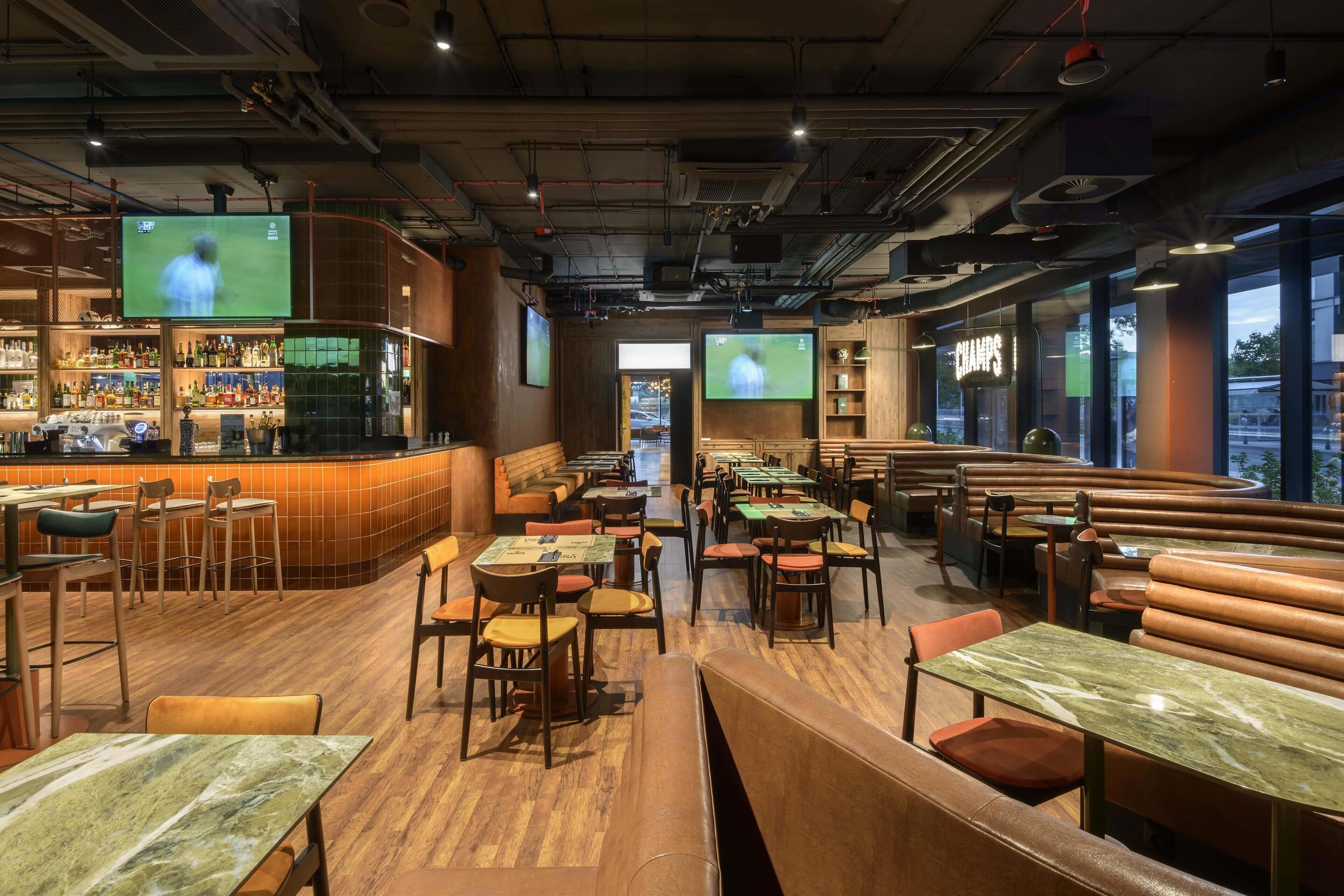 Un restaurante con cabinas, mesas y una zona de bar.