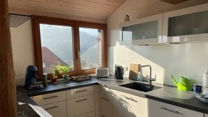 A kitchen with a window, a sink, cabinets, and a microwave.