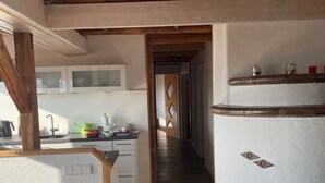 A kitchen with wooden beams, white cabinets, and a wooden countertop.