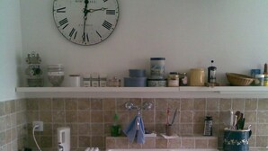 A kitchen with a sink, a clock, and a refrigerator.