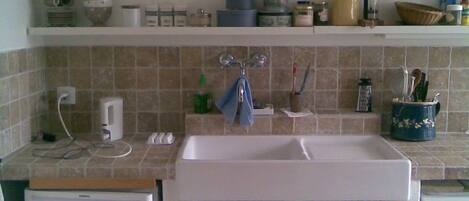 A kitchen with a sink, a clock, and a refrigerator.