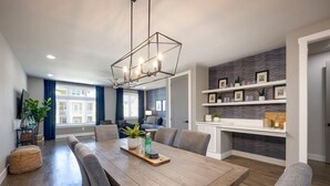 Un comedor moderno con una mesa de madera, sillas tapizadas de color gris y una lámpara colgante de diseño geométrico.