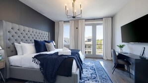 Una habitación de hotel moderna con una cama grande, un escritorio y un televisor.