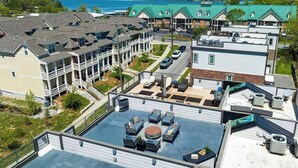 Un barrio residencial con varias casas de dos pisos, un patio en la azotea con muebles de exterior y vista a un lago.
