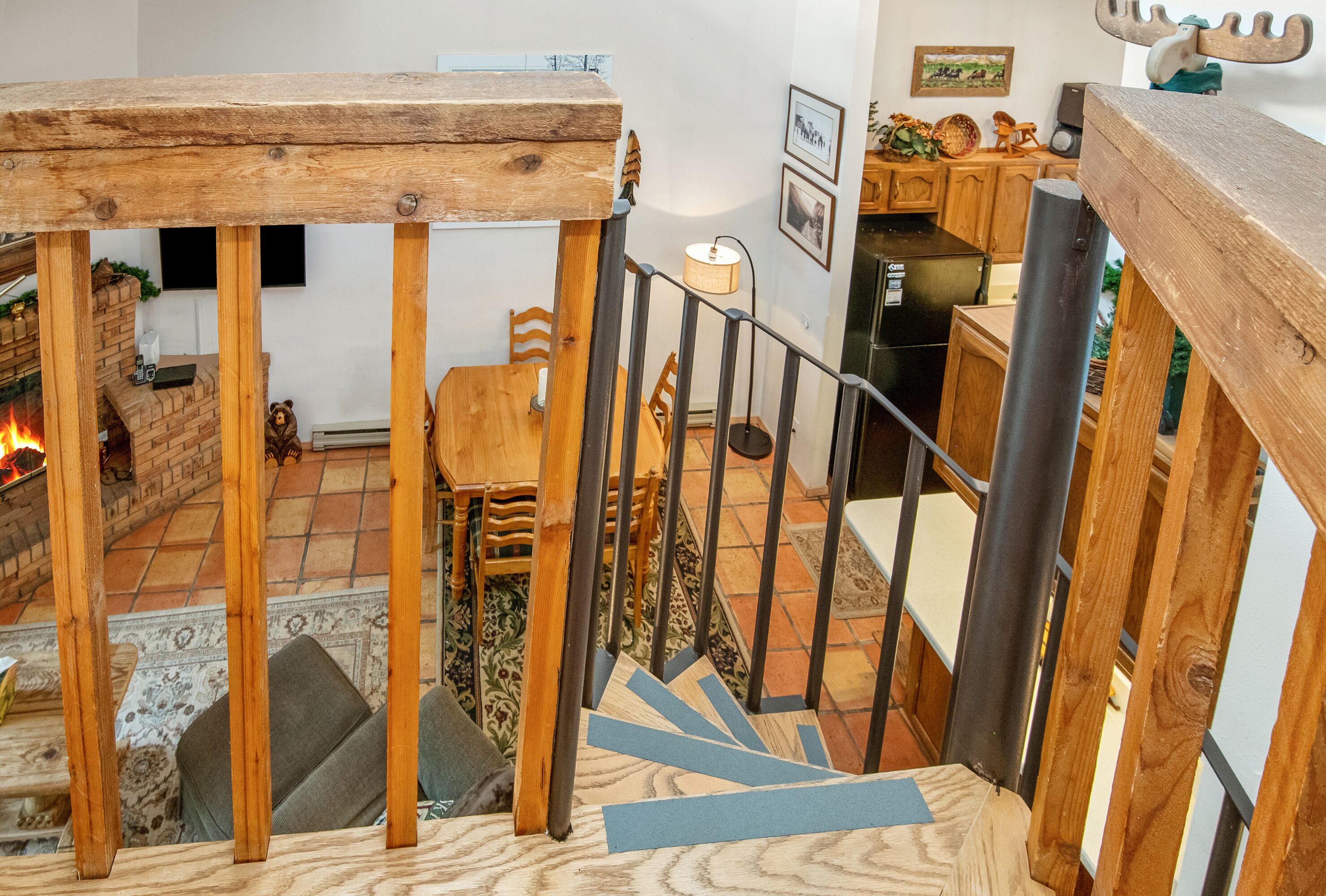 A wooden staircase with a railing, leading to a dining area with a table and chairs.