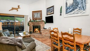 Ein gemütliches Wohnzimmer mit Kamin, einem Esstisch mit Stühlen und einer Couch.