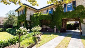 Una casa de dues plantes amb un camí de pedra que porta a l'entrada, envoltada per un jardí ben cuidat amb plantes florentes.
