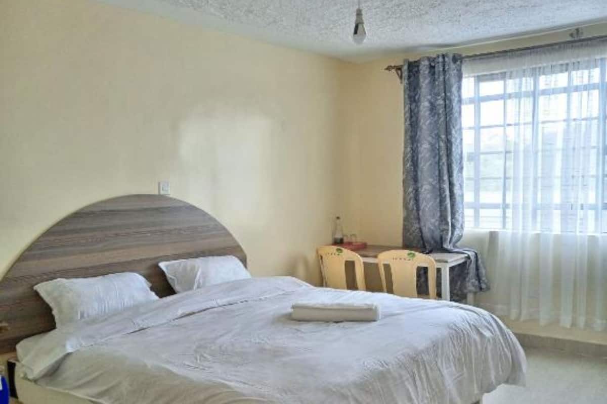 Une chambre à coucher avec un lit, une chaise, une table et une fenêtre avec des rideaux.