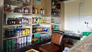 Un espace bar avec des étagères remplies de diverses boissons alcoolisées et de canettes.