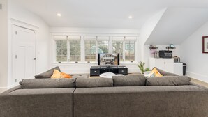 A modern living room with a grey sofa, a flat-screen TV, and a dining table. - Tudor Style Carriage House  (Ann Arbor)