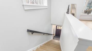 A staircase with a wooden handrail and white walls.