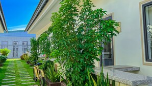 A pathway leading to a building with a tiled roof and a garden area with various plants and a bicycle. - Areca Muine Homestay (Mui Ne)