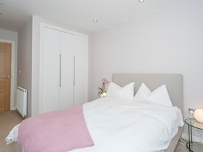 Une chambre à coucher avec un lit, une table de chevet avec une lampe, un radiateur et une armoire.