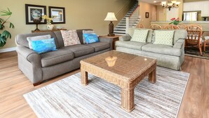 A living room with a grey sofa, a wicker coffee table, and a patterned rug. - 5 BR Beach House in Surfside Beach with Private Pool! C-Batical (Surfside Beach)