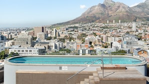 A rooftop pool with a "No Diving" sign, overlooking a cityscape with buildings and mountains in the background. - Designer Apartment at the Peak of Bo-Kaap | Pool (Cape Town)