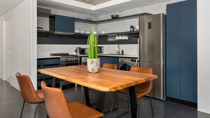 A modern kitchen with a wooden dining table, brown chairs, and a potted plant. - Designer Apartment at the Peak of Bo-Kaap | Pool (Cape Town)