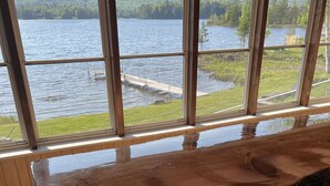 A wooden bar with a view of a lake through large windows. - Cottage on Akers Pond (Errol)