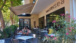 An outdoor cafe with tables and chairs, surrounded by greenery and flowers. - Vinsea Hotel (Bellaria-Igea Marina)
