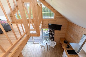 Un intérieur en bois comprenant un coin repas, une table avec des chaises, un téléviseur et une fenêtre donnant sur un paysage naturel.