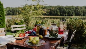 Une table à manger installée à l’extérieur, sur laquelle on trouve une variété de fruits, de légumes et de condiments.