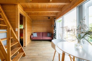 L’intérieur d’un chalet en bois, avec un canapé, une table à manger et un escalier.