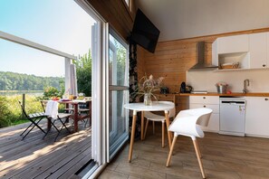 Une cuisine moderne avec un coin repas, un plancher en bois et une vue sur l’extérieur.