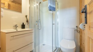 Une salle de bain avec une douche à parois de verre, des toilettes et un lavabo, avec une serviette suspendue au-dessus.
