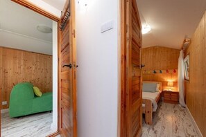 Ein Holzinnenraum mit einem Bett, einem grünen Sofa und einer weißen Wand.