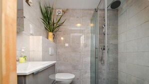 Un baño moderno con inodoro, lavabo y zona de ducha.