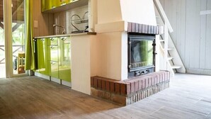 A modern kitchen with green cabinets, a fireplace, and a wooden floor. - Holiday home with a terrace, right by the lake (Klepnica)