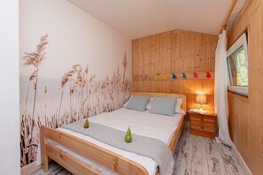 A bedroom with a wooden bed, a nightstand, a lamp, and a wall mural.