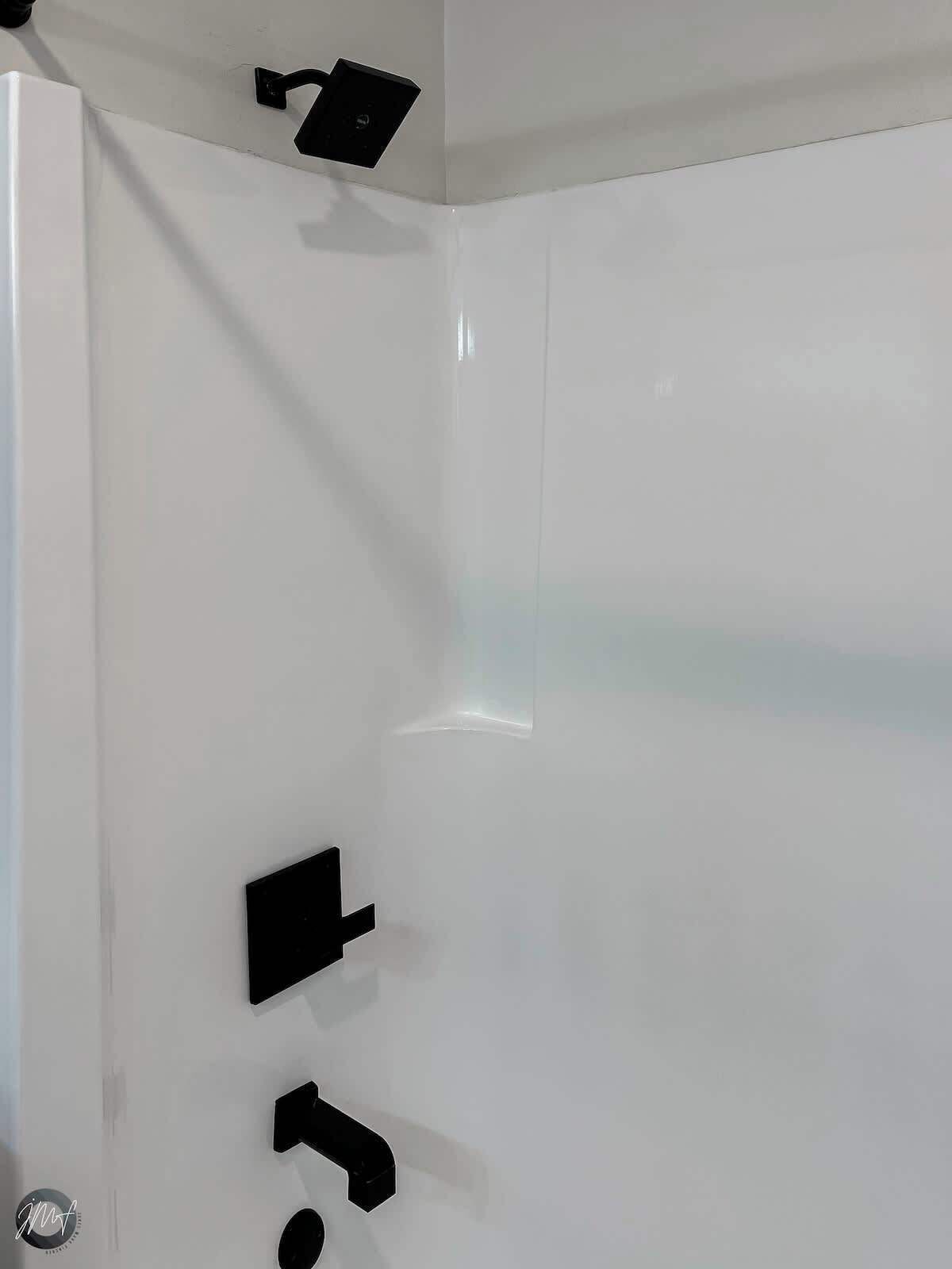 Ein Badezimmer mit weißen Wänden, einer weißen Tür und einem schwarzen Handtuchhalter.