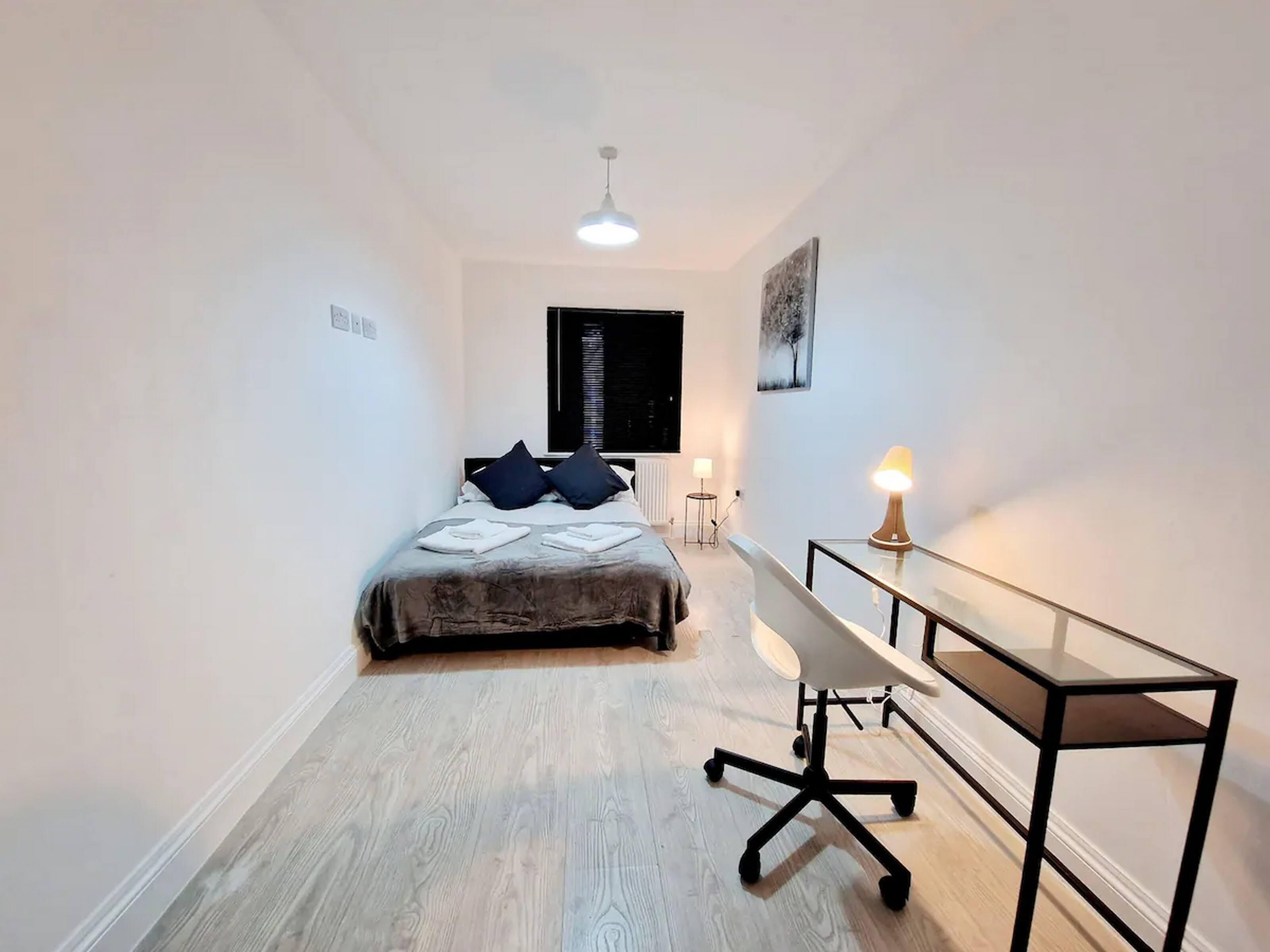 Una camera da letto con un letto, un comodino, una lampada e una scrivania con una sedia.
