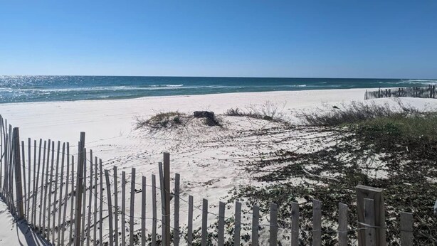 Ein Strand mit einer Holzlattenzaun und freiem Blick auf den Ozean.