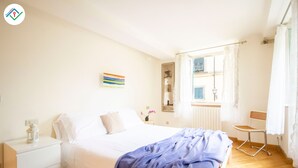 A bedroom with a bed, nightstand, and a window with curtains. - Mezzanine 26 by TuscanyWeGo (Lucca)