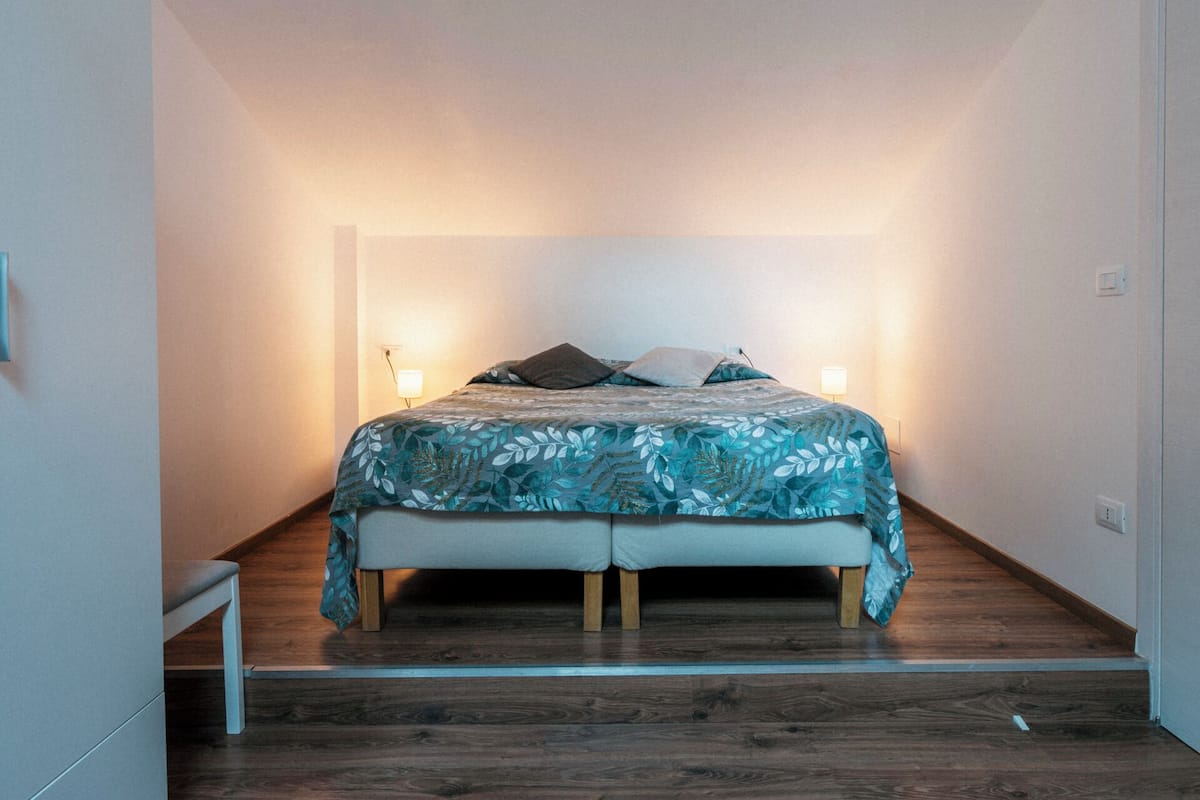 Une chambre à coucher avec un lit, un plancher en bois et deux lampes de chevet.