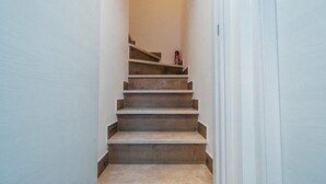 A narrow staircase with wooden steps and a red fire extinguisher on the top step. - Guest House All'83 (Grosseto)