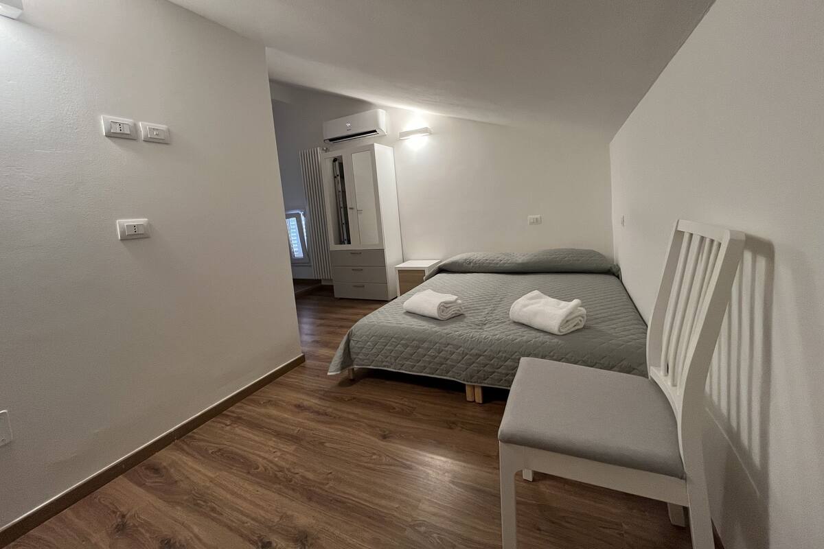 Une chambre à coucher comprenant un lit, une chaise, une armoire et un appareil de climatisation.