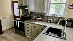 A kitchen with white cabinets, a built-in oven, a sink, and a window with a view of trees. - Quiet secluded home~ minutes from Ocean City boardwalk and beaches (Egg Harbor Township)