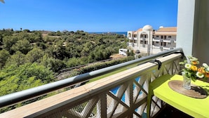 Ein Balkon mit Blick auf eine Küstenlandschaft, eine Überwachungskamera und ein Tisch mit Blumen.