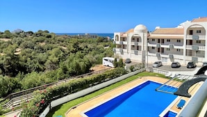Ein Resort mit Schwimmbad, Meerblick und einem weißen Gebäude mit Balkonen.